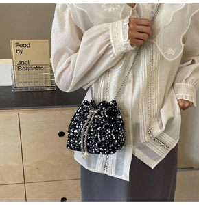 Dettaglio della borsa a secchiello con paillettes nere, catena e nappe di perle