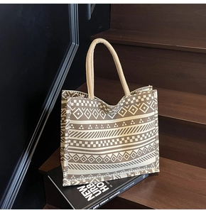 Detail of bohemian canvas tote bag with geometric patterns on wooden stairs with books