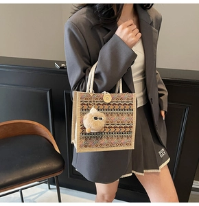 Close-up of ethnic woven pattern tote with wooden button and plush pom-pom charm