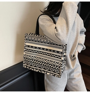 Detail of a large canvas tote bag with black and white geometric ethnic patterns on model