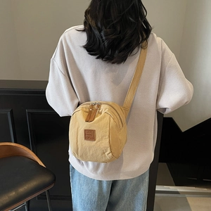 Sac croissant polyvalent en toile kaki avec large bandoulière porté par un mannequin