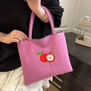 Pink canvas tote bag featuring red apple embroidery with a stylish minimalist design