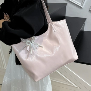 Pink glossy leather tote bag with pearl lace bow charm shown on model in a modern setting
