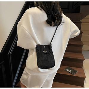 Close-up of lightweight black crossbody phone bag with striped strap on a person