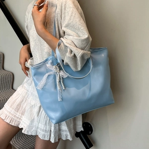 Light blue faux leather tote bag with lace bow and pearl charm worn on shoulder