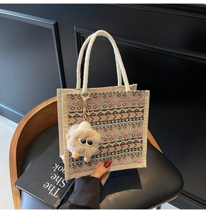 Macro detail of ethnic woven tote bag with cotton rope handles and a plush monster charm