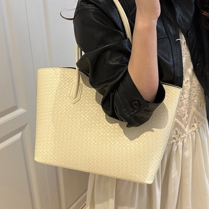 Minimalist beige woven tote bag shown on shoulder for a stylish summer look