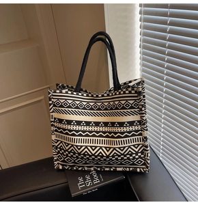 Detailed close-up of geometric pattern canvas tote with black woven rope handles on a sofa