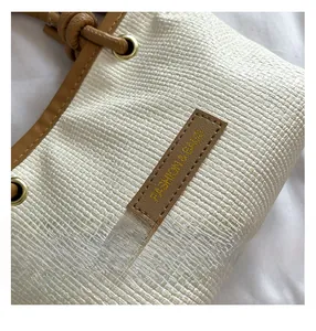 Macro shot of woven beige fabric with brown leather trim and fashion brand tag detail