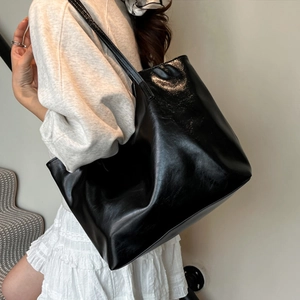 Minimalist black glossy leather tote bag with large capacity shown on a model