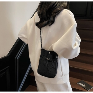 Mini black nylon drawstring crossbody bag shown from a stylish model back view
