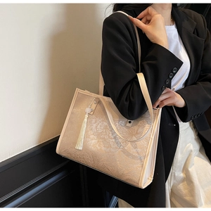 Close-up of beige vintage floral tote bag with silk tassel detail on model shoulder