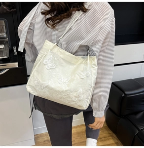 Detail of creamy white silk shoulder bag with delicate 3D butterfly floral embroidery