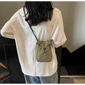 Detailed view of olive green drawstring crossbody bag with textured fabric and rope strap