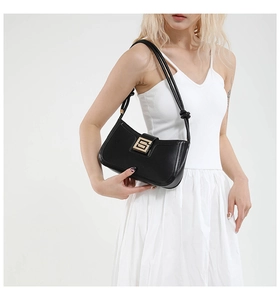 Detail of black leather shoulder bag with golden buckle and minimal dual strap knots