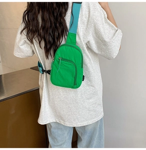 Détail du sac bandoulière en nylon vert vif avec sangle bleue porté par un mannequin