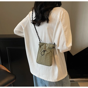 Close-up of olive green nylon crossbody bag with drawstring closure worn by model