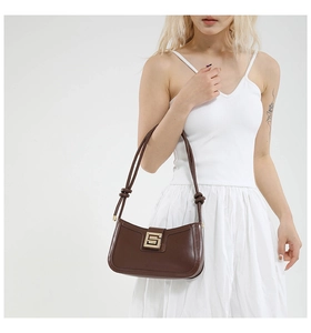 Detail of dark brown leather baguette bag with a geometric gold metal buckle
