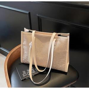 Detail of light beige tote bag with 3D floral texture and elegant white tassel charm