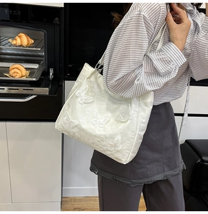 Detail of white shoulder bag with 3D butterfly embroidery in a kitchen setting