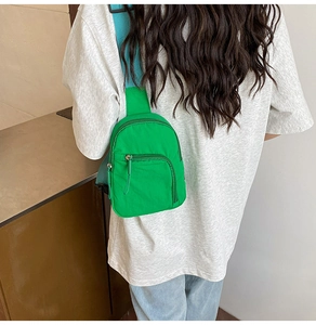 Détail du sac bandoulière en nylon vert avec sangle bleue porté par le mannequin de dos