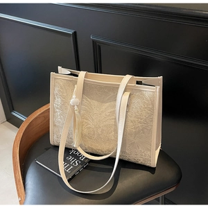 Close-up of cream jacquard tote bag with leaf texture and fringe tassel detail