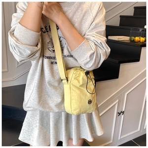 Close-up of lightweight yellow nylon crossbody bag with drawstring closure and wide strap
