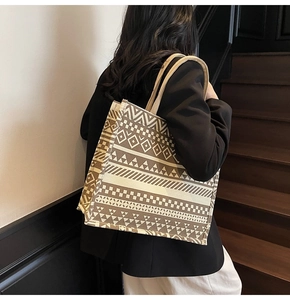 Close-up of beige canvas tote bag with brown ethnic geometric patterns on a shoulder strap