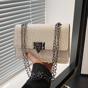 Ivory quilted crossbody bag with metal chain strap and rivet clasp in natural light