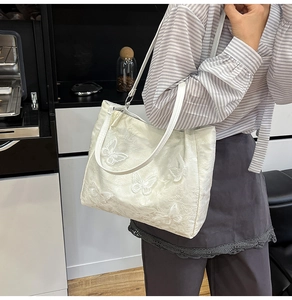 Detail of elegant white silk-textured shoulder bag with 3D butterfly embroidery motifs