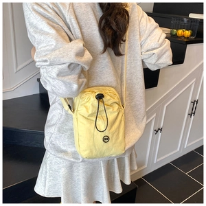 Detail of yellow nylon crossbody bag with drawstring closure and metal DIW logo
