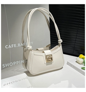 Detailed macro shot of a cream-white leather shoulder bag with a square gold metal buckle