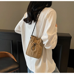 Detailed view of khaki folding crossbody bag with drawstring lock and woven adjustable strap