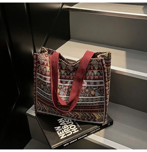 Close-up of bohemian woven tote bag with colorful geometric patterns and red canvas straps