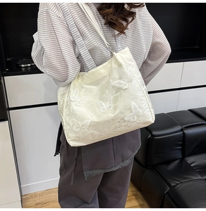 Close-up of white tote bag with floral 3D butterfly embroidery and jacquard texture