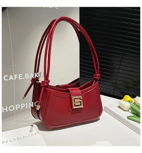 Detail of red leather shoulder bag with gold square buckle and minimalist knotted strap