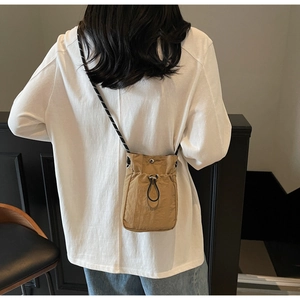 Close-up of khaki drawstring crossbody phone bag with textured fabric and woven strap