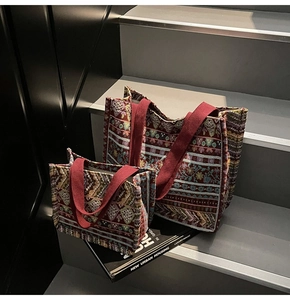 Detail view of two bohemian tote bags with red jacquard patterns on gray stairs