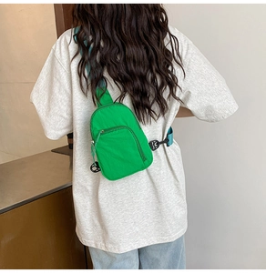 Détail du sac bandoulière en nylon vert vif avec sangle bleue porté par le mannequin