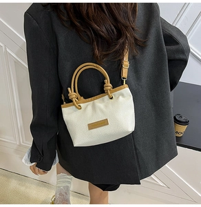 Detail of woven straw tote bag with brown leather handles and fashion logo patch