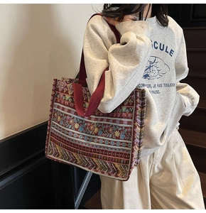 Close-up of bohemian woven tote bag with ethnic patterns and red canvas straps