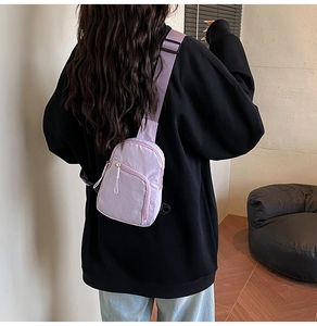 Détail du sac bandoulière en nylon lavande avec sangle réglable sur un sweat noir