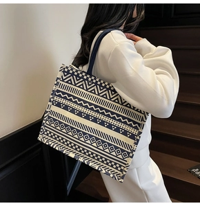 Detailed view of large canvas tote bag with blue geometric patterns on model