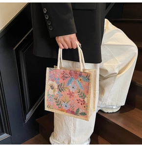 Detail der floralen Web-Tote-Bag mit cremefarbenen Seilgriffen vor schwarzer Wand