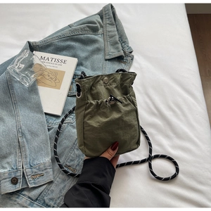 Detailed view of an olive green nylon mini crossbody bag on denim fabric with outdoor styling