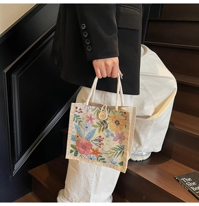 Detail einer floralen Jacquard-Tasche mit Seilgriffen und Holzknopf-Verschluss