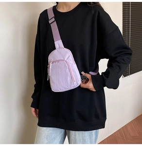 Détail du sac de poitrine en nylon lilas avec bandoulière sur un sweat-shirt noir