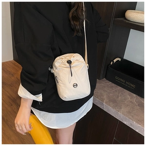 Rear view of a model wearing the cream nylon drawstring crossbody bag for size reference