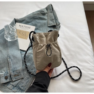 Detail of khaki nylon crossbody bag with drawstring pocket and woven cord strap