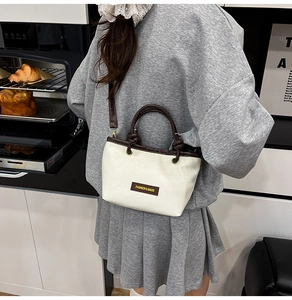 Close-up of beige woven bucket bag featuring brown leather handles and metal hardware